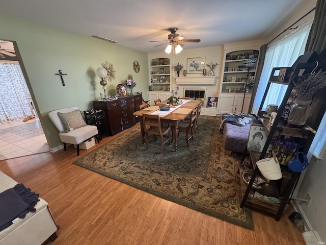 8133 Maple Ln, Newburgh, IN 47630 - dining room with a ceiling fan, a fireplace, wood finished floors, and built in features