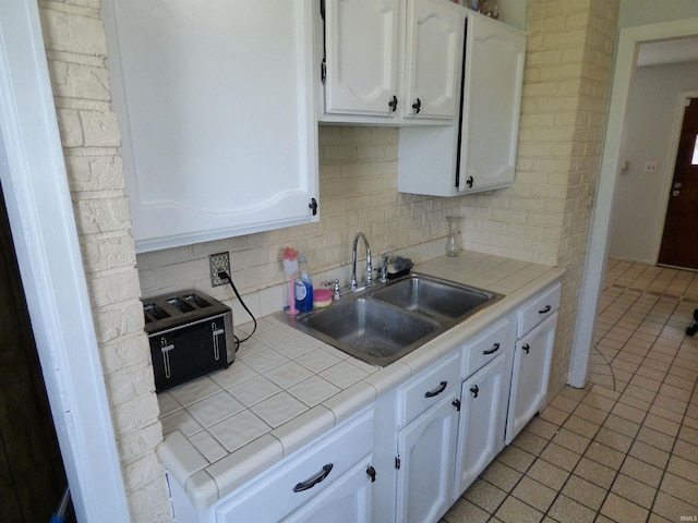1612 N Wellington St, South Bend, IN 46628 - kitchen with tile countertops, a sink, white cabinetry, backsplash, and light tile patterned flooring