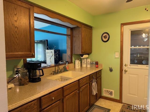 1402 E Culver Rd, Knox, IN 46534 - kitchen featuring a sink, light countertops, baseboards, and brown cabinetry