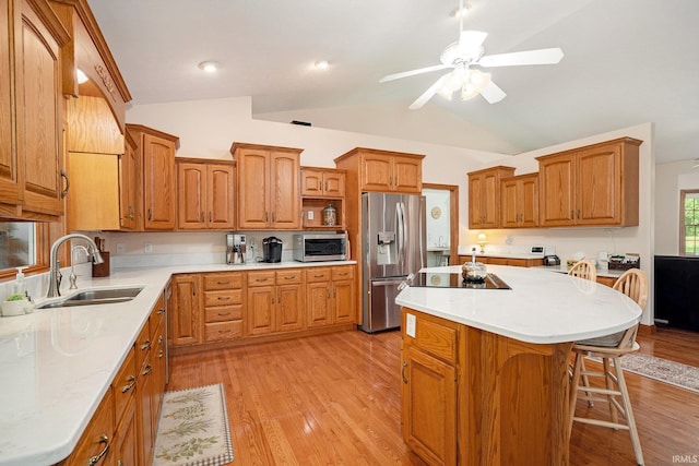 2617 W Union St, Claypool, IN 46510 - kitchen with stainless steel appliances, a sink, vaulted ceiling, brown cabinetry, and light wood-style flooring