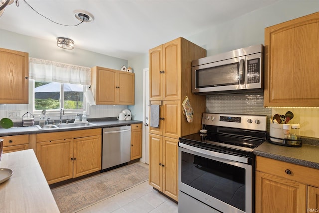 12678 Pat Ln, Granger, IN 46530 - kitchen featuring stainless steel appliances, a sink, backsplash, light tile patterned floors, and dark countertops