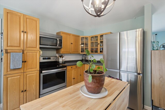 12678 Pat Ln, Granger, IN 46530 - kitchen featuring stainless steel appliances, a chandelier, glass insert cabinets, and decorative backsplash