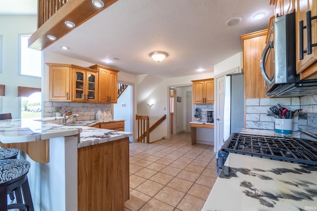 4609 N Sheldon Dr, Churubusco, IN 46723 - kitchen featuring tasteful backsplash, a sink, a peninsula, a breakfast bar area, and a textured ceiling