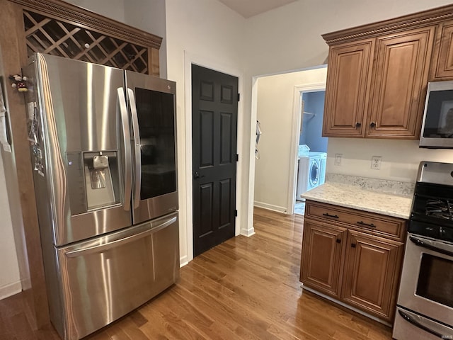 8284 S Mackenzie Ct, Bloomington, IN 47401 - kitchen featuring stainless steel appliances, washing machine and clothes dryer, wood finished floors, light stone countertops, and baseboards