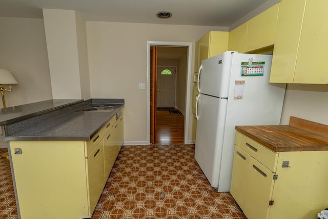 3314 Whitcomb Ave, South Bend, IN 46614 - kitchen featuring dark flooring, freestanding refrigerator, dark countertops, cream cabinets, and a peninsula