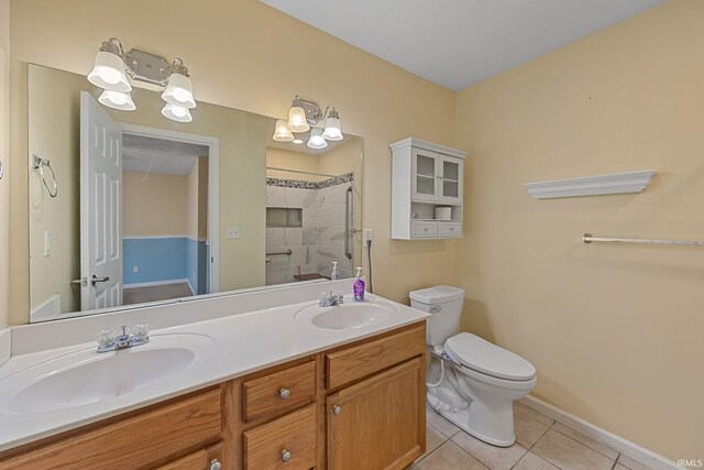 1890 Cal Dr, West Lafayette, IN 47906 - bathroom featuring tile patterned floors, a tile shower, toilet, double vanity, and baseboards