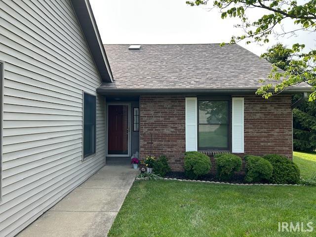 3915 S Allen Ct, Bloomington, IN 47401 - view of exterior entry featuring roof with shingles, a yard, and brick siding