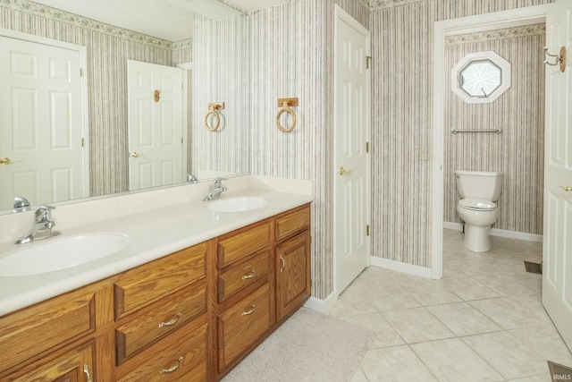 3915 S Allen Ct, Bloomington, IN 47401 - bathroom with wallpapered walls, double vanity, tile patterned flooring, toilet, and baseboards