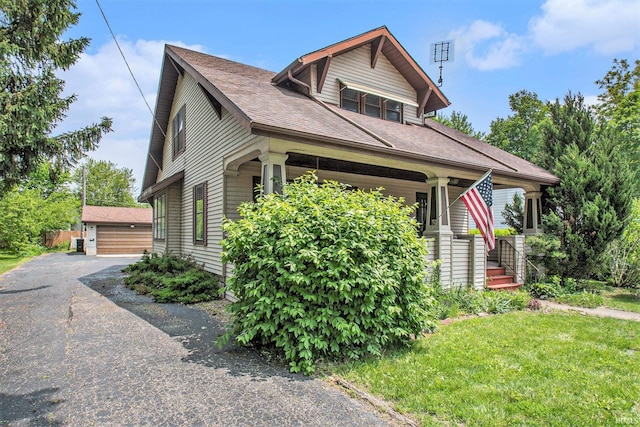 419 S First St, Pierceton, IN 46562 - view of front of house with an outbuilding, a porch, roof with shingles, a detached garage, and a front lawn