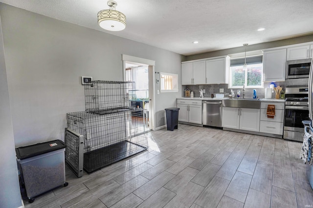 104 N Jefferson St, Pine Village, IN 47975 - kitchen with stainless steel appliances, a sink, wood finish floors, decorative backsplash, and a textured ceiling