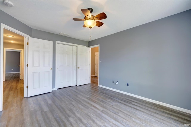 1063 S Colchester Ct, Bloomington, IN 47401 - unfurnished bedroom with wood finished floors, baseboards, a closet, and a ceiling fan