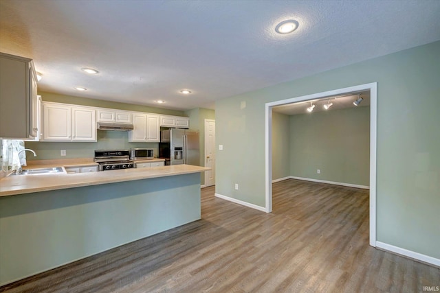 1063 S Colchester Ct, Bloomington, IN 47401 - kitchen featuring stainless steel appliances, a sink, baseboards, a peninsula, and light countertops