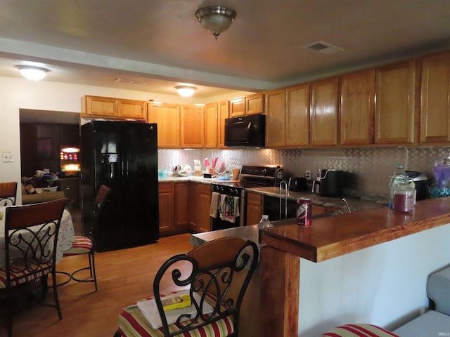 303 S Lenfesty Ave, Marion, IN 46952 - kitchen featuring black appliances, a peninsula, backsplash, and light wood-type flooring