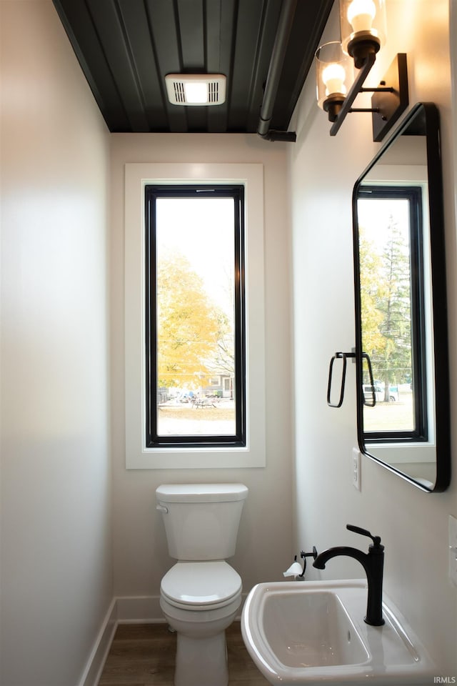 904 E Berry St, Fort Wayne, IN 46803 - half bathroom with a sink, toilet, wood finished floors, and baseboards