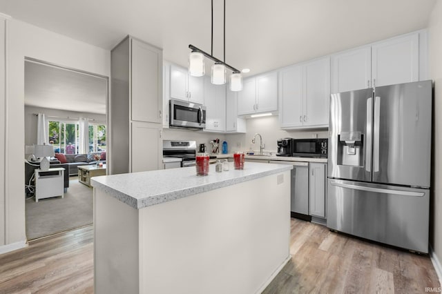 1210 Mcintyre Dr, Auburn, IN 46706 - kitchen featuring appliances with stainless steel finishes, a sink, light wood-type flooring, a kitchen island, and pendant lighting