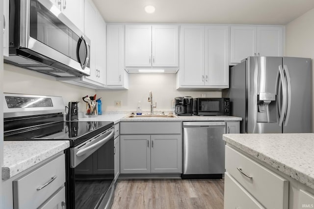 1210 Mcintyre Dr, Auburn, IN 46706 - kitchen with appliances with stainless steel finishes, a sink, light wood-type flooring, white cabinets, and recessed lighting