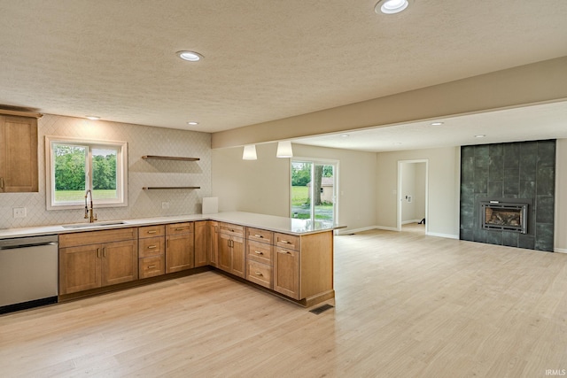2135 Old Oak Dr, West Lafayette, IN 47906 - kitchen with stainless steel dishwasher, a sink, light countertops, brown cabinetry, and a peninsula