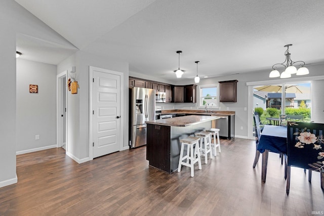 15926 Continental Dr, Huntertown, IN 46748 - kitchen featuring appliances with stainless steel finishes, dark brown cabinetry, a kitchen island, dark wood-style flooring, and baseboards