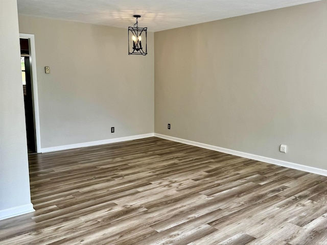 42 Center St, Avoca, IN 47420 - spare room with wood finished floors, baseboards, and a chandelier