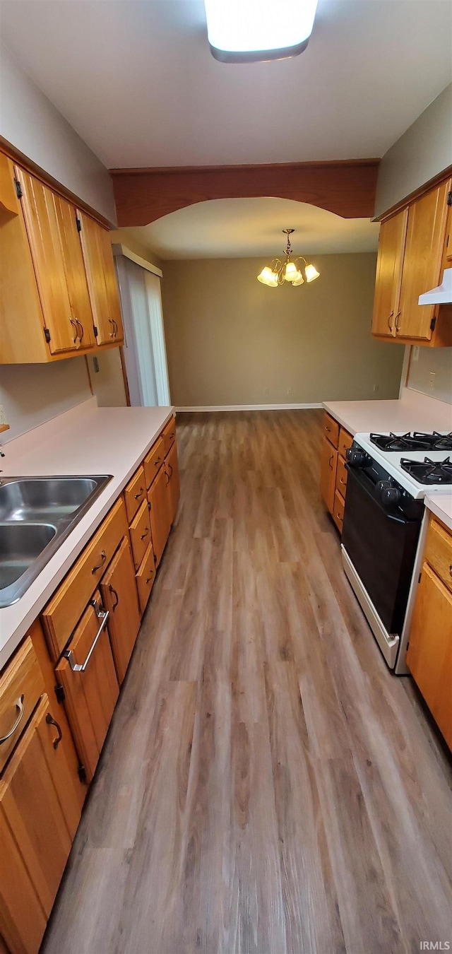 1609 Gordon Dr, Kokomo, IN 46902 - kitchen with gas stove, a sink, light wood finished floors, ventilation hood, and a chandelier