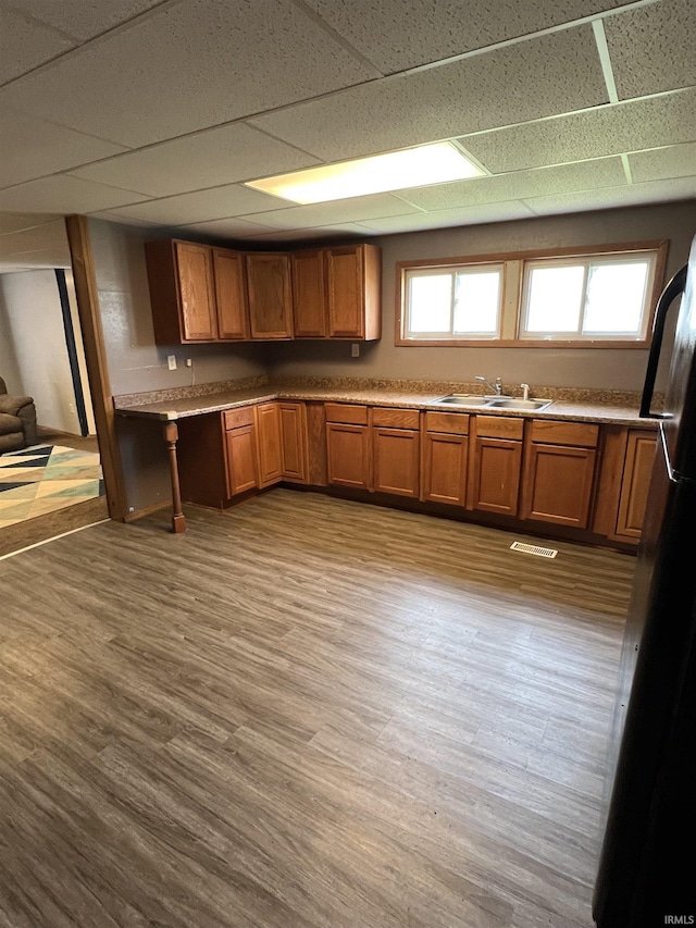 443 S State St, Sullivan, IN 47882 - kitchen with brown cabinetry, a paneled ceiling, freestanding refrigerator, wood finished floors, and a sink