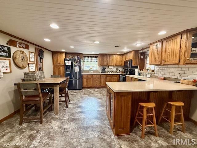 981 Keyser Ln, Richmond, IN 47374 - kitchen featuring black fridge with ice dispenser, electric stove, brown cabinetry, a peninsula, and a breakfast bar area