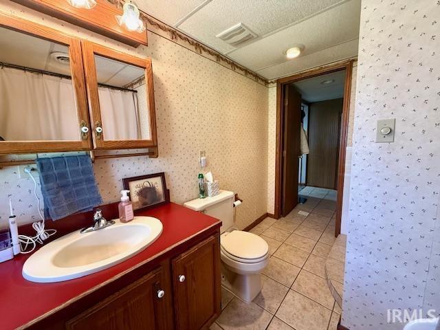 981 Keyser Ln, Richmond, IN 47374 - bathroom featuring toilet, vanity, tile patterned flooring, wallpapered walls, and curtained shower