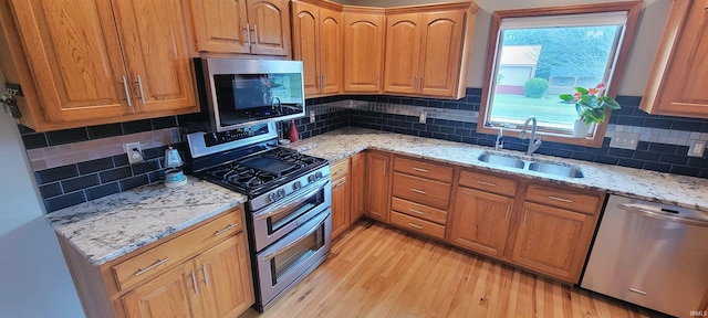 360 E 350 Rd N, Warsaw, IN 46582 - kitchen featuring stainless steel appliances, a sink, light wood finished floors, light stone counters, and tasteful backsplash
