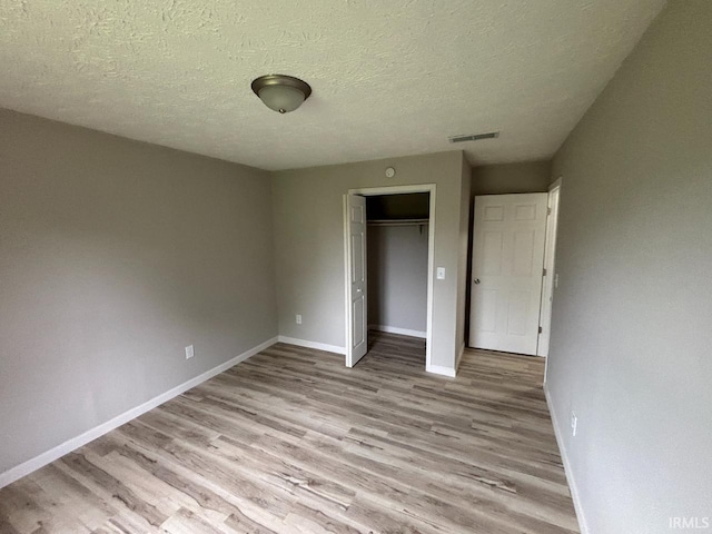 724 Iroquois Dr, Anderson, IN 46012 - unfurnished bedroom with light wood-type flooring, baseboards, a closet, and a textured ceiling