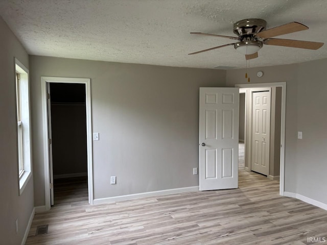724 Iroquois Dr, Anderson, IN 46012 - unfurnished bedroom featuring light wood finished floors, a textured ceiling, a spacious closet, baseboards, and a closet