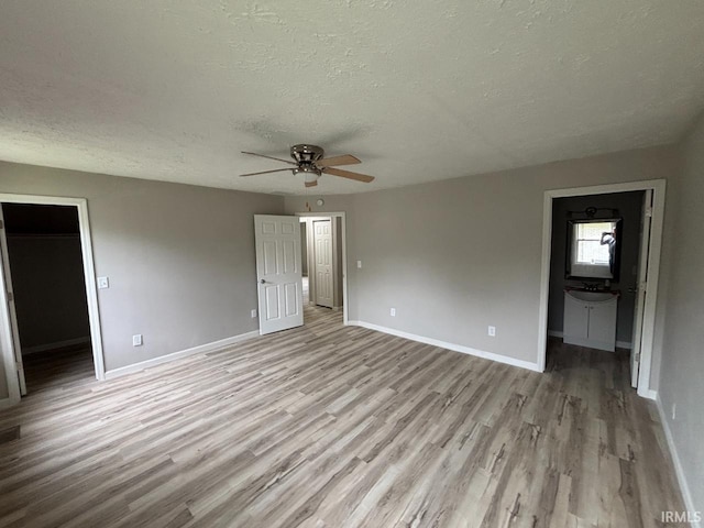 724 Iroquois Dr, Anderson, IN 46012 - unfurnished bedroom with a textured ceiling, light wood finished floors, baseboards, a spacious closet, and ensuite bath