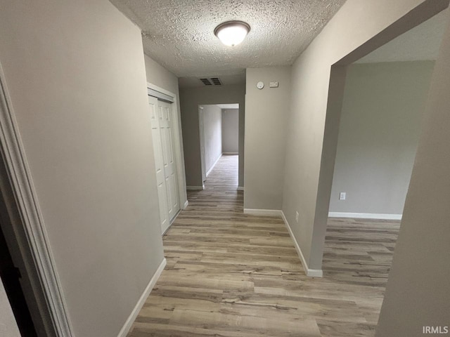 724 Iroquois Dr, Anderson, IN 46012 - hallway featuring light wood-type flooring, a textured ceiling, and baseboards