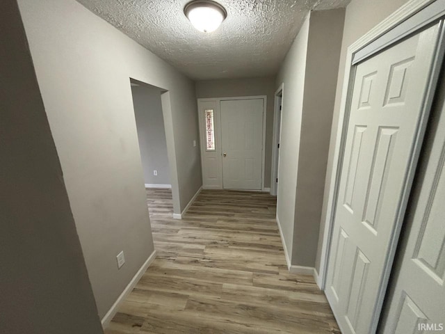 724 Iroquois Dr, Anderson, IN 46012 - hallway featuring light wood-style flooring, a textured ceiling, and baseboards
