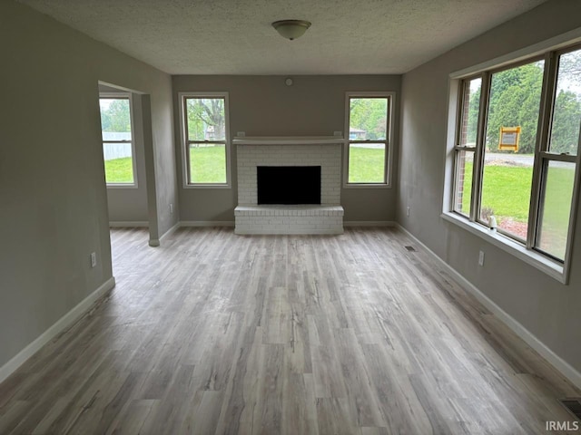724 Iroquois Dr, Anderson, IN 46012 - unfurnished living room with wood finished floors, a textured ceiling, healthy amount of natural light, and baseboards