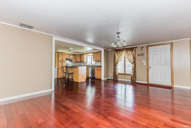 7782 S Warren Rd, Warren, IN 46792 - unfurnished living room featuring a chandelier, dark wood finished floors, baseboards, and crown molding