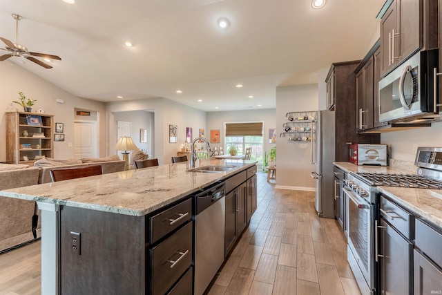 7937 Boydon Ct, Evansville, IN 47715 - kitchen with appliances with stainless steel finishes, open floor plan, dark brown cabinetry, a kitchen island with sink, and light stone countertops