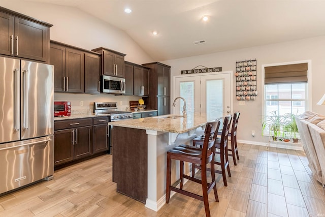 7937 Boydon Ct, Evansville, IN 47715 - kitchen with premium appliances, a sink, vaulted ceiling, a breakfast bar area, and light stone countertops