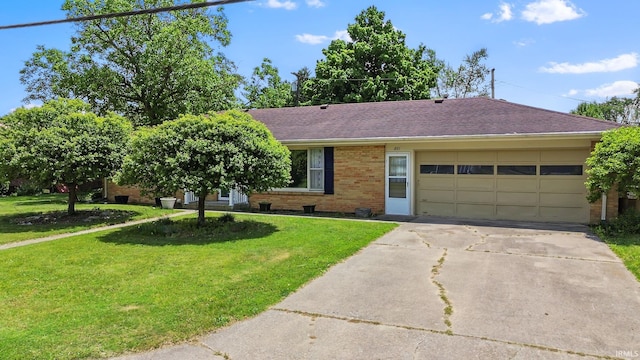 211 Condo St, Monticello, IN 47960 - ranch-style home featuring a garage, concrete driveway, a front yard, brick siding, and a shingled roof