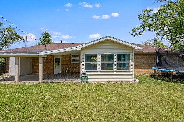 211 Condo St, Monticello, IN 47960 - back of house with a trampoline, a yard, brick siding, and a deck