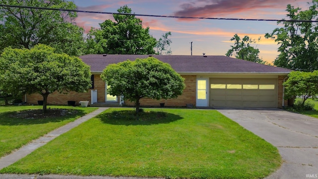 211 Condo St, Monticello, IN 47960 - view of front of house with driveway, an attached garage, a lawn, brick siding, and roof with shingles