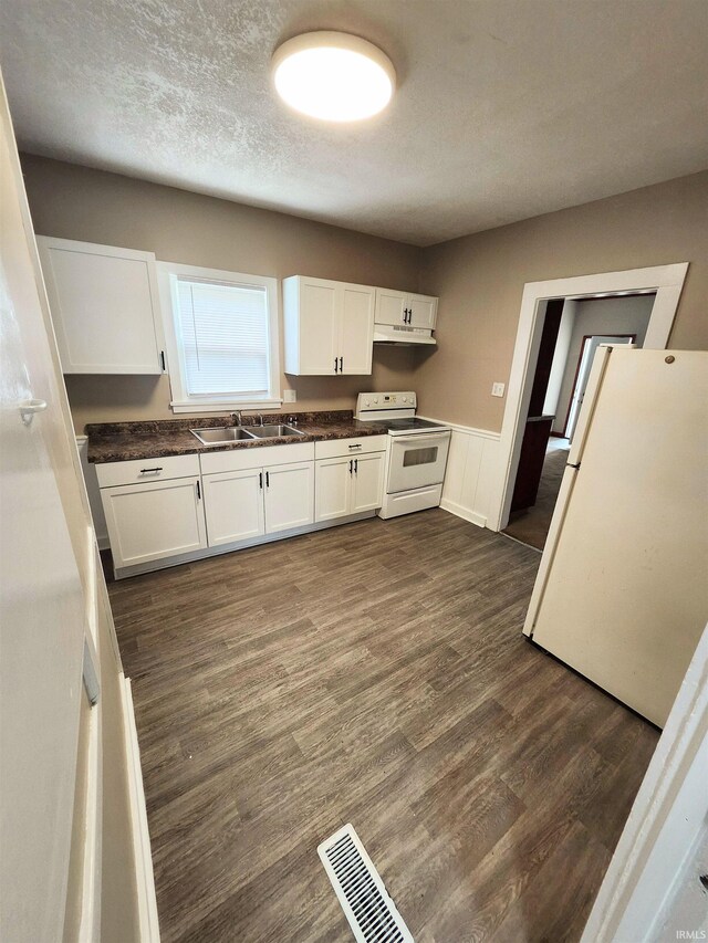 436 E Taber St, Fort Wayne, IN 46803 - kitchen with white appliances, under cabinet range hood, a sink, white cabinets, and dark countertops