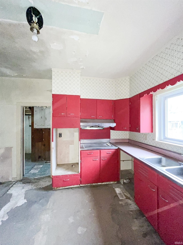 402 W Elm St, Gaston, IN 47342 - kitchen featuring red cabinetry, under cabinet range hood, cooktop, wallpapered walls, and concrete floors