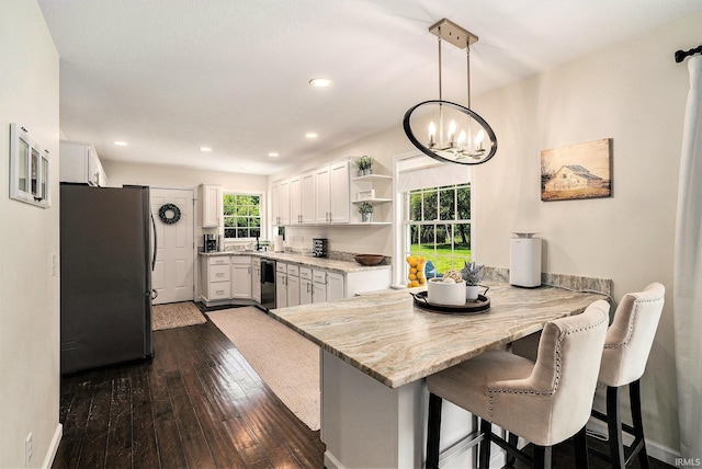 58201 Windsong Dr, Elkhart, IN 46517 - kitchen with freestanding refrigerator, a peninsula, a chandelier, white cabinets, and a kitchen bar