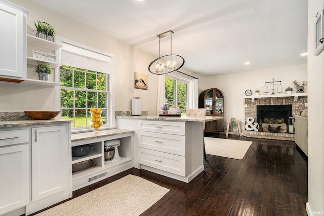 58201 Windsong Dr, Elkhart, IN 46517 - kitchen with open shelves, a peninsula, white cabinets, a fireplace, and dark wood finished floors