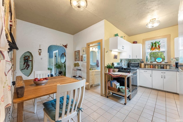 1712 High St, Fort Wayne, IN 46808 - kitchen featuring stainless steel range with gas cooktop, white cabinetry, a sink, light tile patterned floors, and a textured ceiling