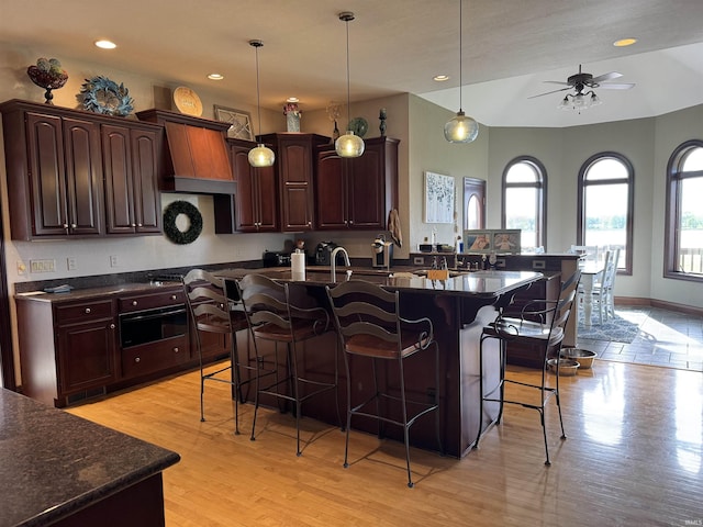 5533 N 150 Rd E, Urbana, IN 46990 - kitchen featuring dark countertops, oven, a breakfast bar, ceiling fan, and a center island with sink