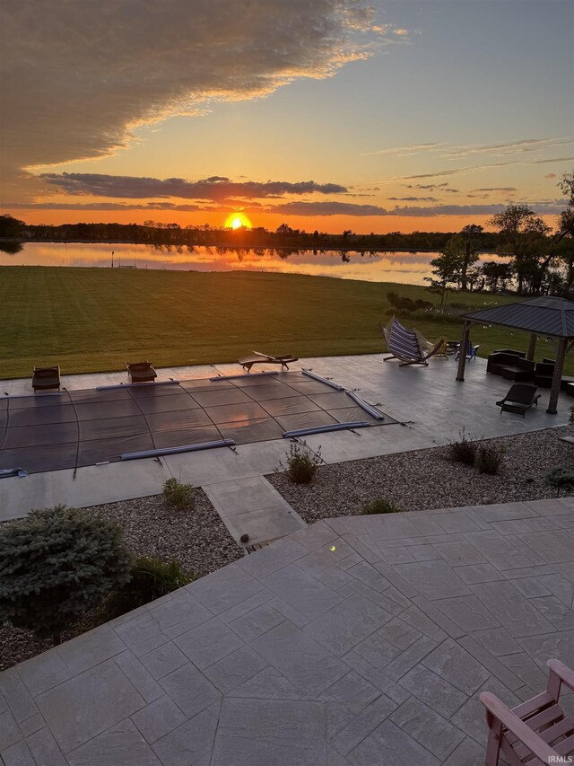 5533 N 150 Rd E, Urbana, IN 46990 - patio terrace at dusk with a water view, a patio, a covered pool, and a lawn