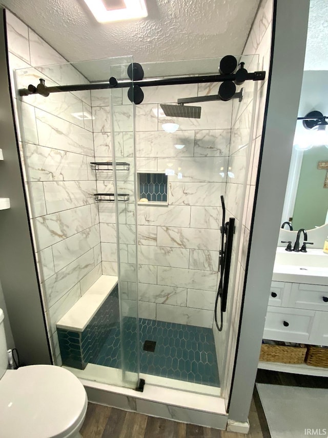 138 N Harrison St, Bloomfield, IN 47424 - bathroom with toilet, vanity, a stall shower, a textured ceiling, and wood finished floors