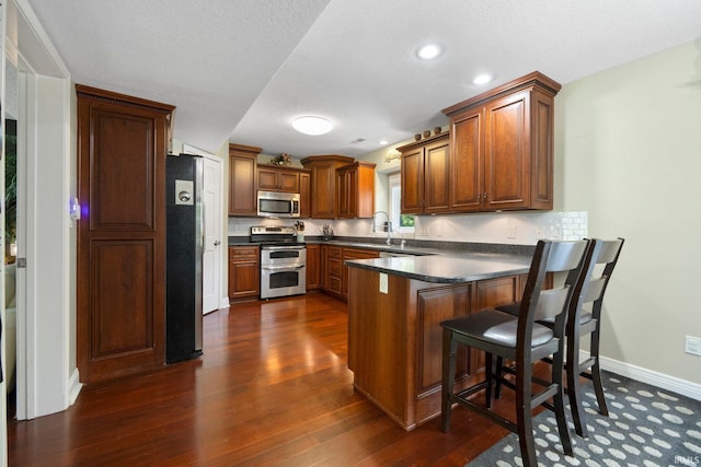 16316 Thunderbird Rd, Huntertown, IN 46748 - kitchen featuring appliances with stainless steel finishes, a peninsula, dark wood finished floors, and dark countertops