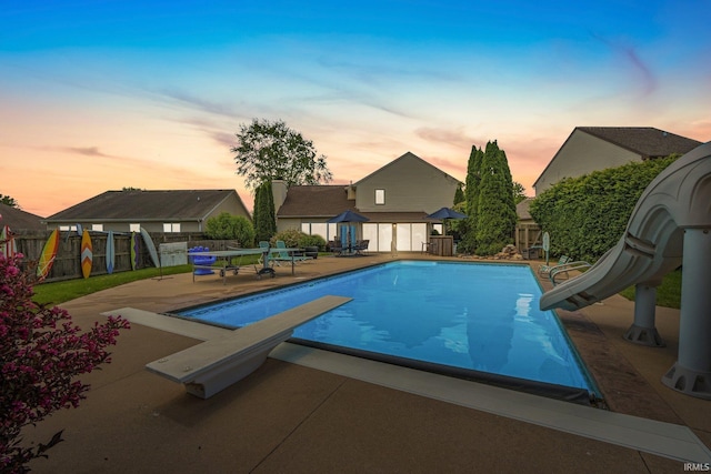 16316 Thunderbird Rd, Huntertown, IN 46748 - pool at dusk with a water slide, a diving board, a patio, and a fenced backyard